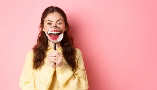 Woman holding a magnifying glass over her smile